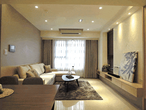 沒有華麗裝飾，而是運用溫潤木色與簡單素色壁面的搭配，營造溫馨感。沙發背牆結合兩種材質，拉長素色壁紙的高度，製造挑高空間的錯覺。
