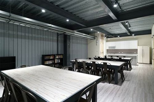 員工餐廳用木紋塑膠地板、木紋磚餐桌，搭配白色廚具，營造簡約俐落空間。